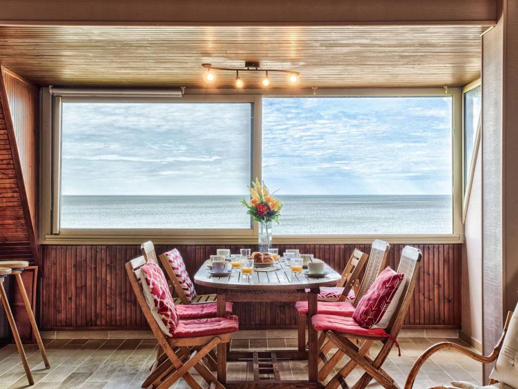 une salle à manger avec une table et des chaises et une grande fenêtre dans l'établissement Appartement en duplex avec piscine chauffée, idéal pour 6 personnes - FR-1-788-61, à Varaville