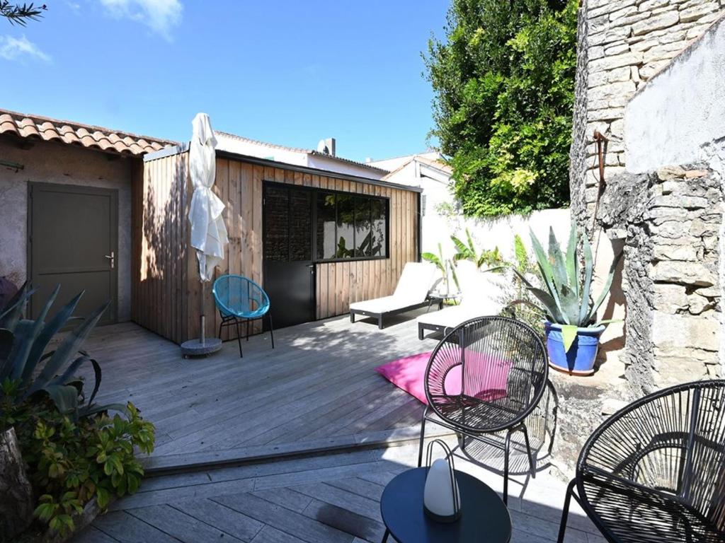un patio avec des chaises et des tables sur une terrasse en bois dans l'établissement Charmante Maison de Village au Cœur de La Couarde-sur-Mer - FR-1-434-119, à La Couarde-sur-Mer