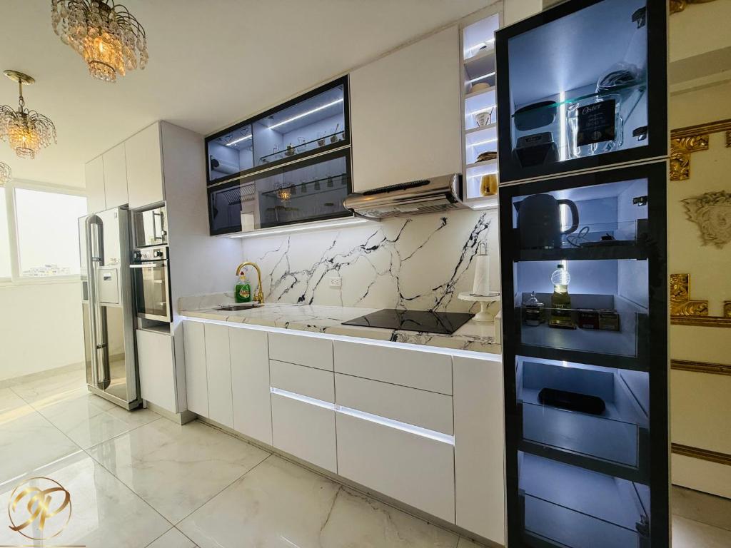 Una cocina con gabinetes blancos y un refrigerador de acero inoxidable. en El Palacio del Rey, en Lima