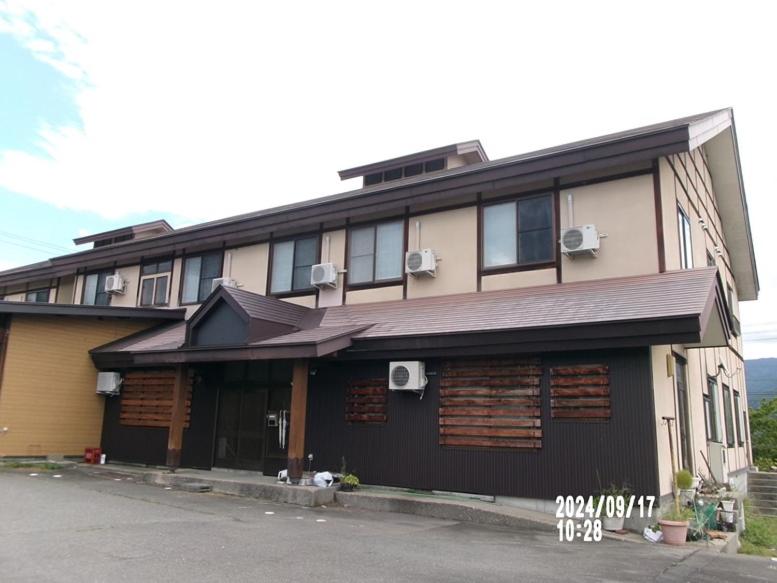 un gran edificio con techo de gambrel en una calle en Famille Wakata, en Hakuba