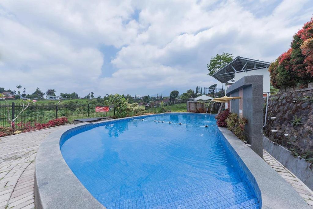 a large blue swimming pool in a yard at Mamifokobo Hotel & Glamping in Sindanglaya
