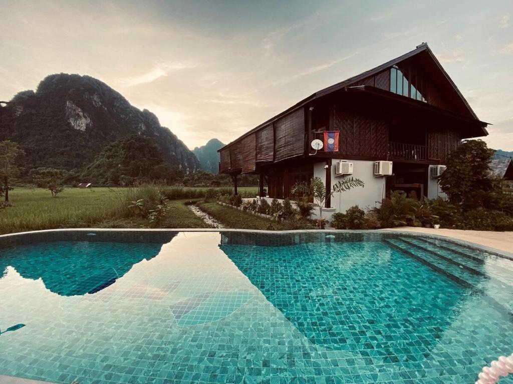 ein Haus mit einem Swimmingpool vor einem Gebäude in der Unterkunft Dalasone Pool Villa with Stunning Mountain View in Vang Vieng