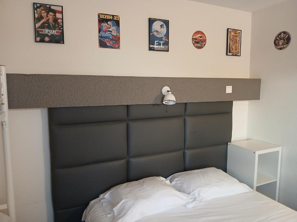 - un lit avec une tête de lit noire et des photos au-dessus dans l'établissement hôtel QUICK Palace Tours Nord, à Tours