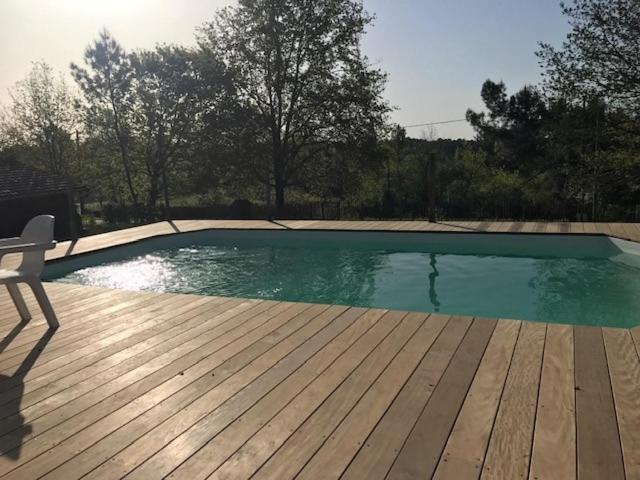a swimming pool with a chair on a wooden deck at Maison de charme - piscine - coeur du Périgord ! in Saint-Georges-de-Blancaneix