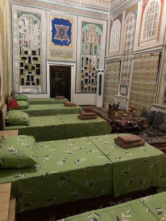 a room with many green beds in a room at Mekhtarin in Bukhara