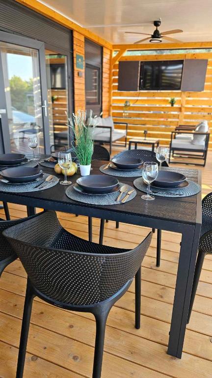 a black table with plates and wine glasses on it at Mobile home Tortuga in Drage