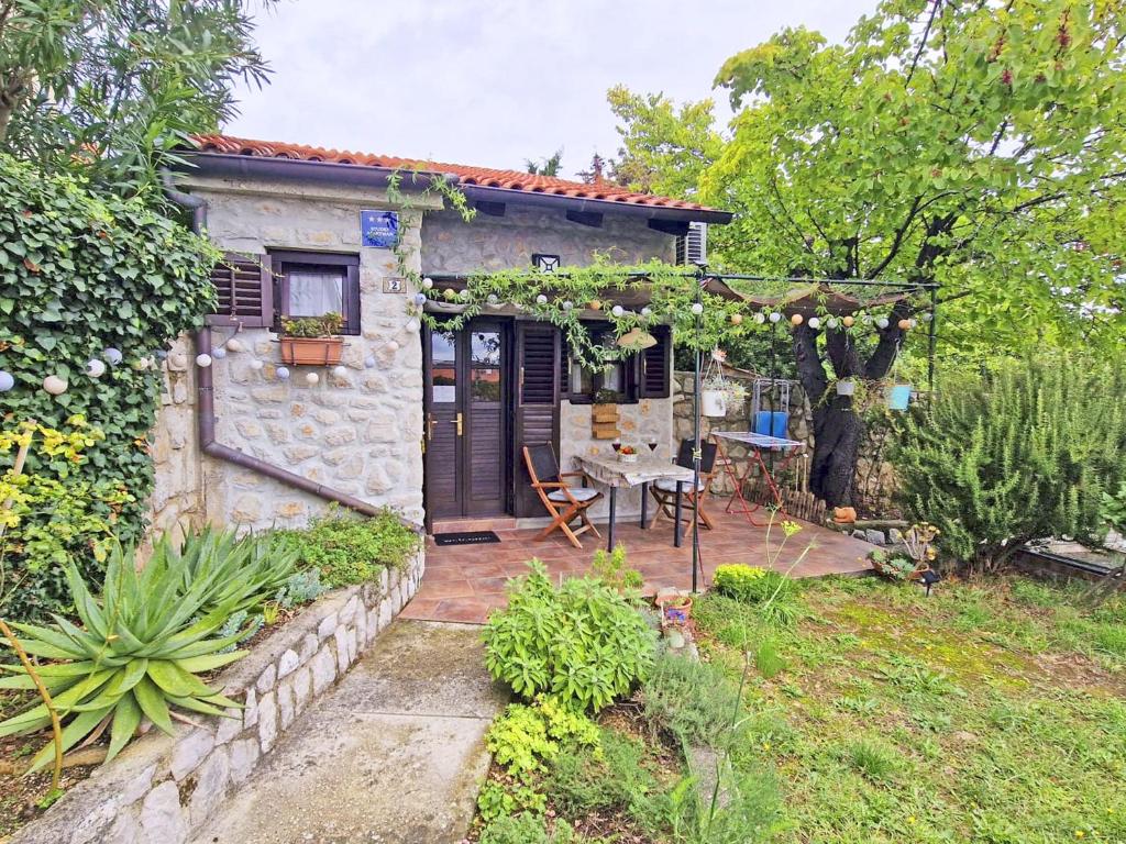 a small house with a patio and a table at Nives Garden house in Nerezine
