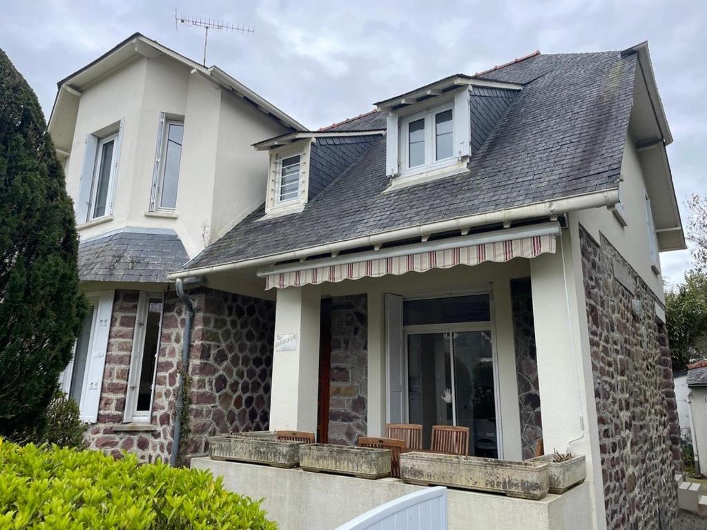 une maison blanche dotée d'une terrasse couverte avec des chaises. dans l'établissement Maison 4 à 6 personnes à Sables d'Or les Pins près de la plage et du golf, à Fréhel