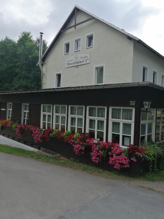 a large white building with flowers in front of it at Gasthaus Pension Bretthäusl in Glashütte