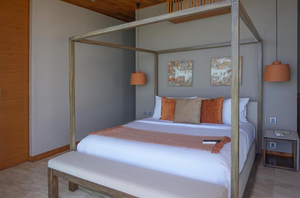 a bedroom with a canopy bed and a bench at Selong Selo Resort and Residences in Selong Belanak