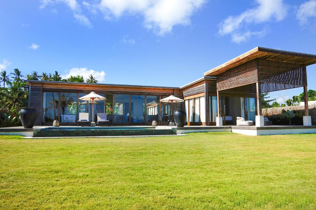a house with a lawn in front of it at Selong Selo Resort and Residences in Selong Belanak