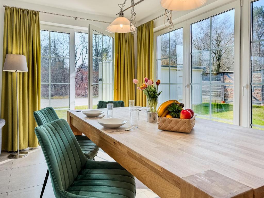 Un comedor con una mesa de madera y sillas verdes. en Windland, en Zingst