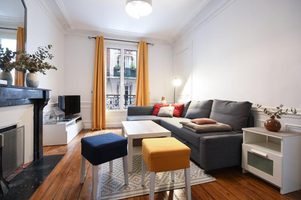 un salon avec un canapé et une cheminée dans l'établissement GuestReady - Charm an Comfort in Épinettes, à Paris
