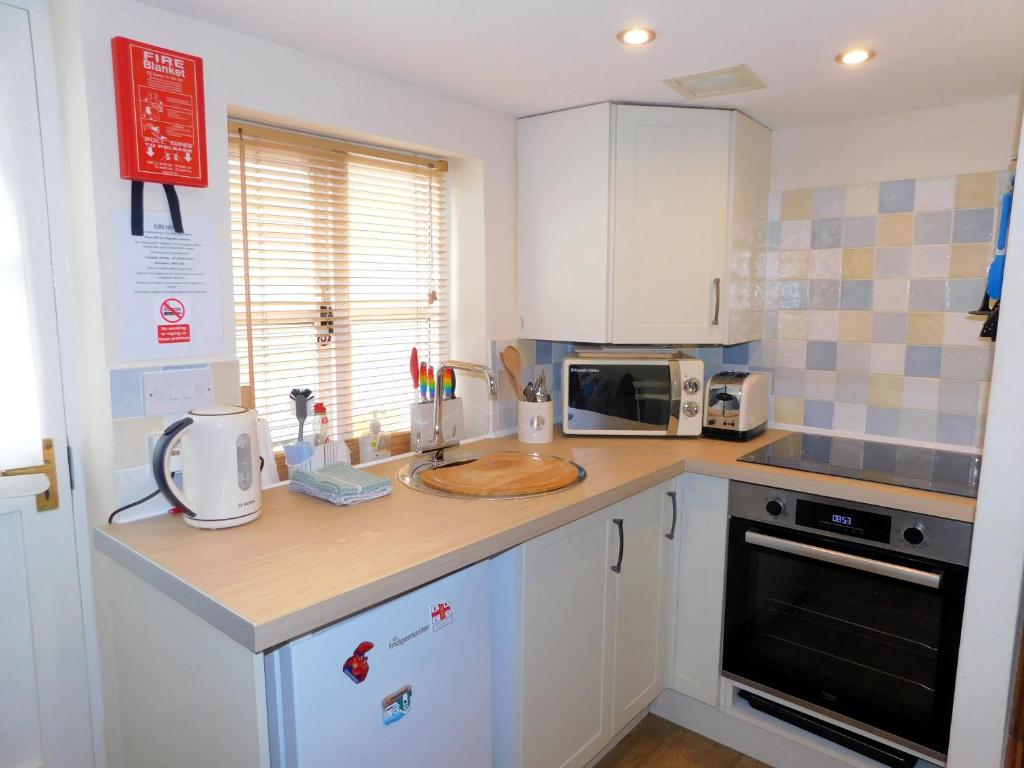 a kitchen with white cabinets and a counter top at 2 Museum Cottages in Sheringham