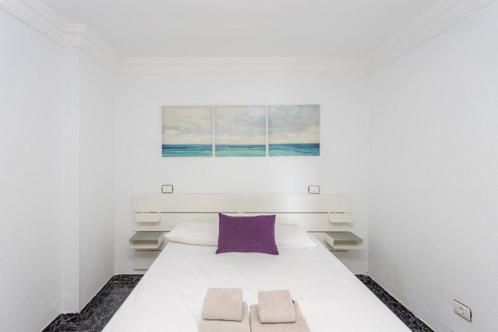 sypialnia z dużym białym łóżkiem z fioletową poduszką w obiekcie Lightbooking playa de Amadores La Concha w mieście Puerto Rico de Gran Canaria