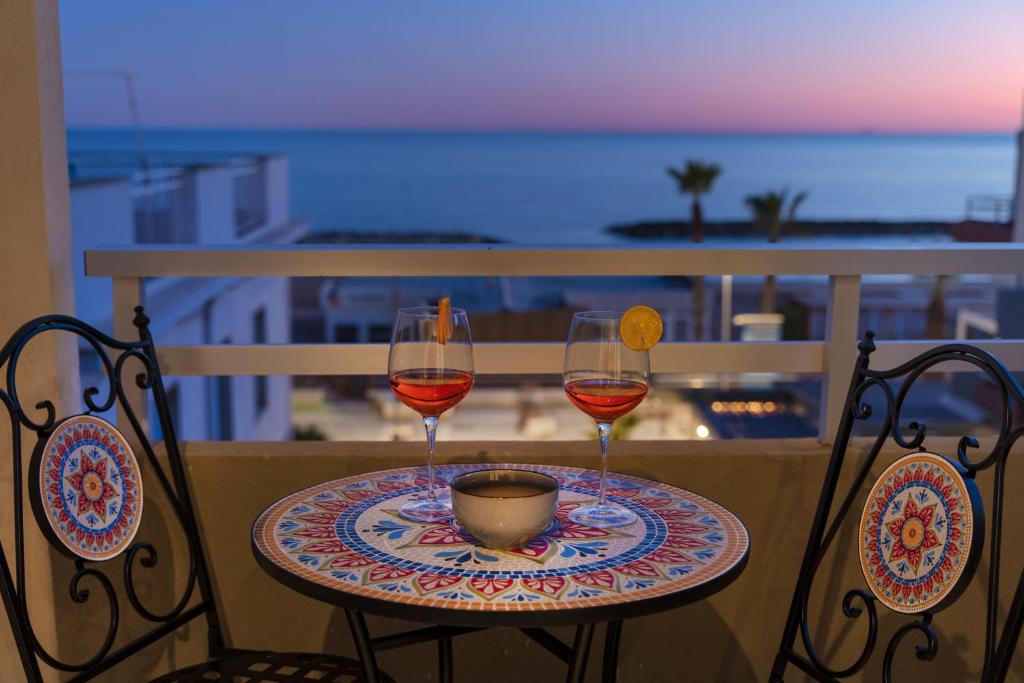zwei Gläser Wein auf einem Tisch auf einem Balkon in der Unterkunft Casa Suli Beachfront in Marina di Ragusa