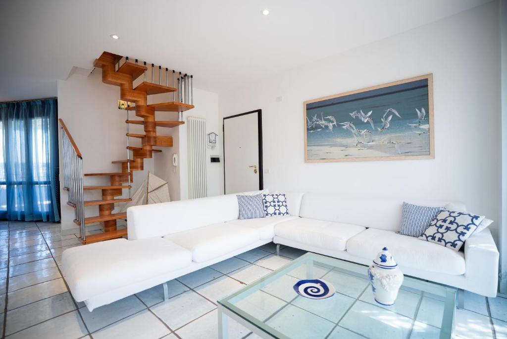 a living room with a white couch and a glass table at Attico La Vela Vista Mare in Cervia