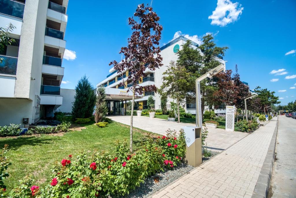 a sidewalk in front of a building with flowers at Astria Mediterana - Complex Novum in Olimp
