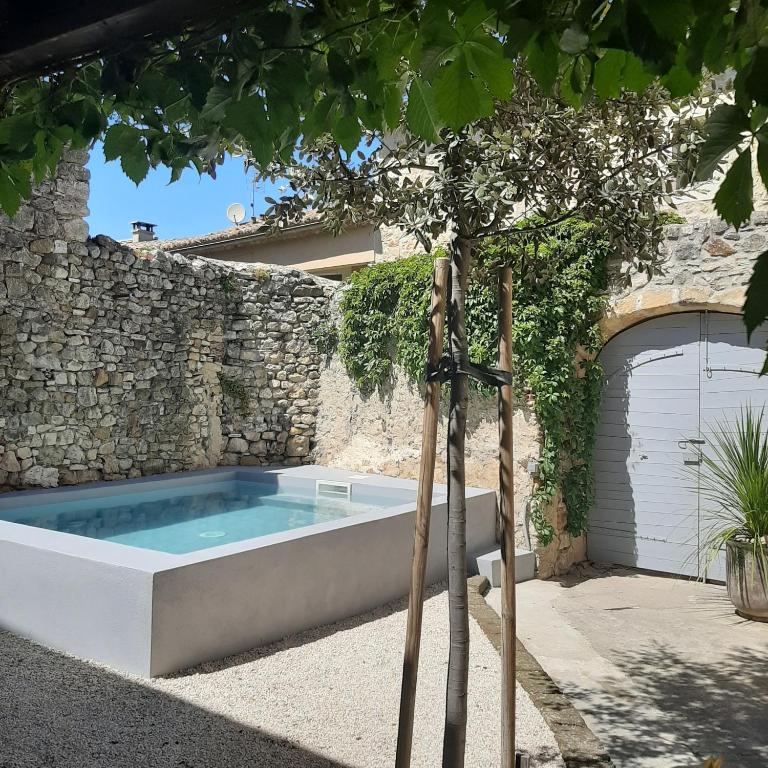 - une piscine en face d'un mur en pierre dans l'établissement Maison Mymoodz, à Cornillon