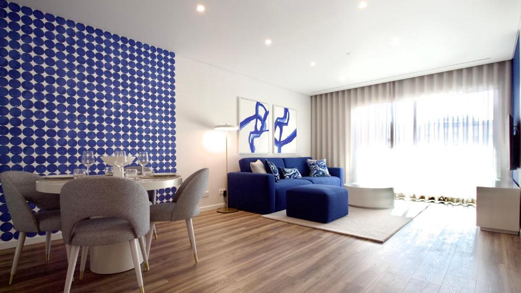 a living room with a table and a blue couch at Orange Boutique Residence - Casa Farol in Quarteira