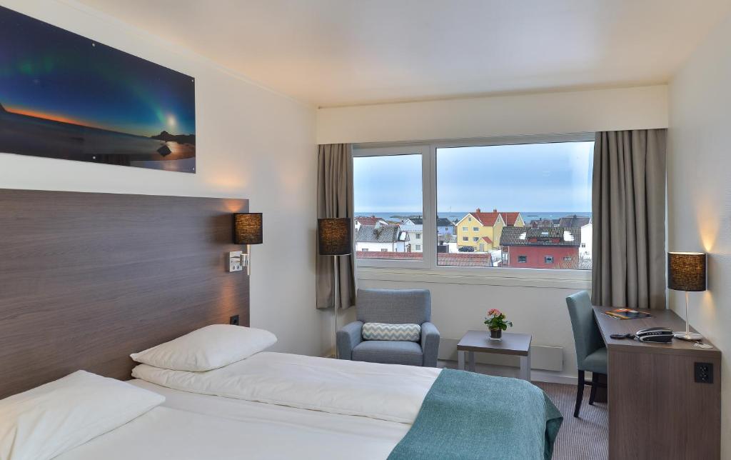 a hotel room with two beds and a desk and a window at Thon Partner Hotel Andrikken in Andenes