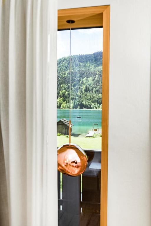 a room with a view of a lake through a window at Biohotel Gralhof in Weissensee
