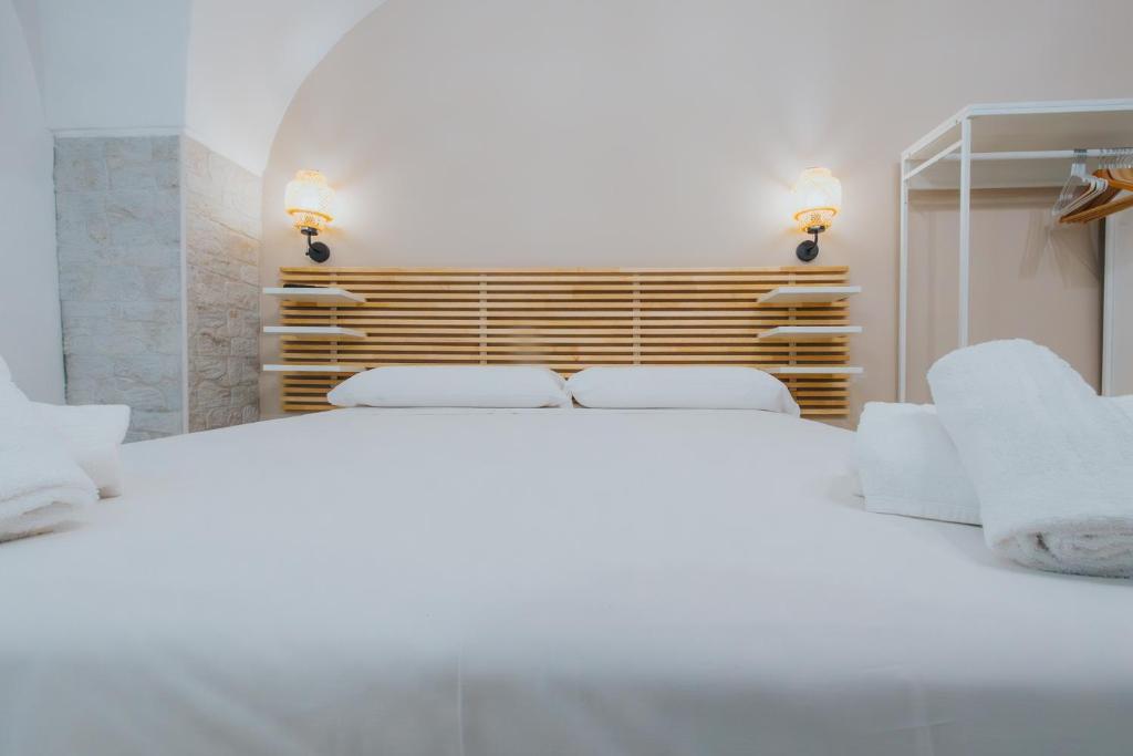 ein weißes Schlafzimmer mit drei Betten und einem Spiegel in der Unterkunft Desire Home in Bari