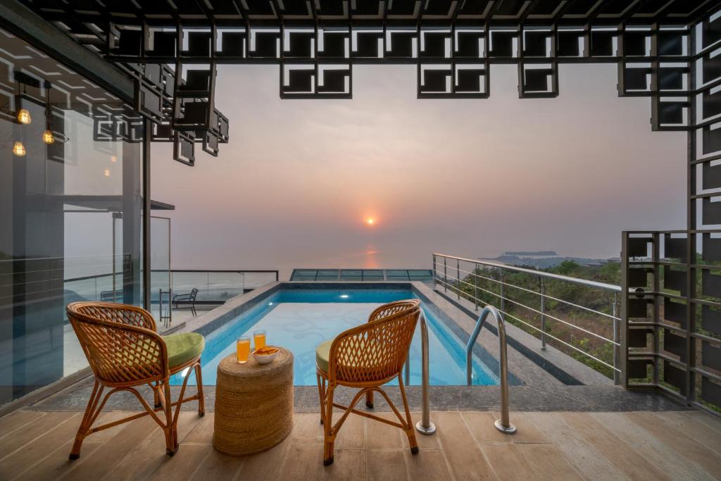 HarnaiSaffronStays Nautica - 5BR hilltop villa with rooftop pool, sea views & modern interiors surrounded by greenery的一座带游泳池和两把椅子的房子