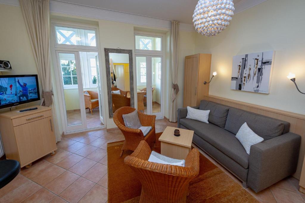 a living room with a couch and chairs and a tv at Villa Malepartus - Wohnung 03 in Binz