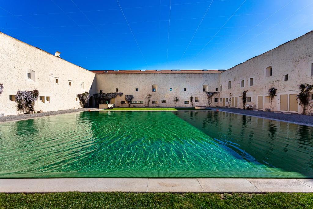 a pool in the courtyard of a building with green water at Tavira Convent, 2-bedroom, condo, pool in Tavira