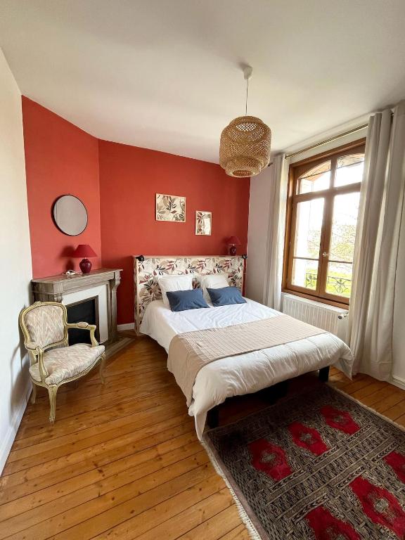 - une chambre avec des murs rouges, un lit et une chaise dans l'établissement Maison meulière du 34e Sacre, à proximité du Domaine Pommery, à Reims