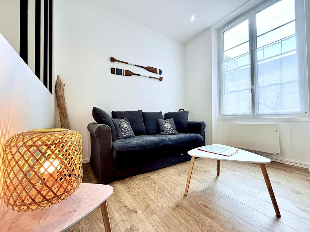 un salon avec un canapé noir et une table dans l'établissement 1738 - T1 Bis Corderie Royale RDC hyper Centre, à Rochefort