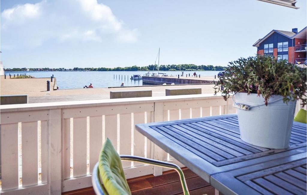 a picnic table with a potted plant on a balcony overlooking the beach at Two-Bedroom Apartment In Grasten in Gråsten