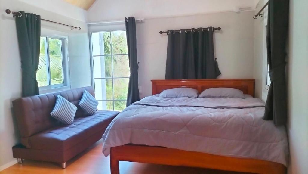 a bedroom with a bed and a couch and windows at Tanakorn House in Thong Nai Pan Yai