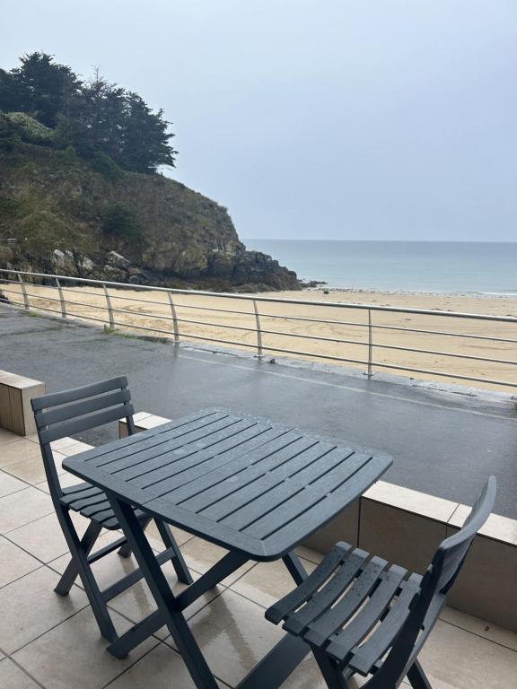 un tavolo da picnic e due sedie su un balcone con vista sulla spiaggia di La terrasse de l'océan a Pléneuf-Val-André