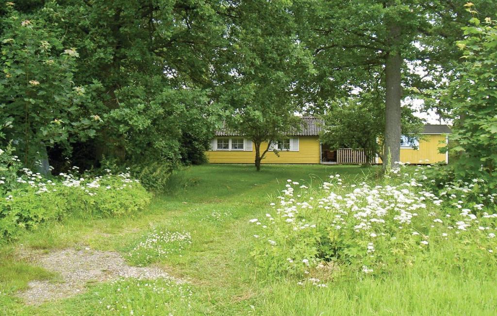 a yellow house in the middle of a yard with flowers at Pet Friendly Home In Ljungby With Wifi in Bolmstad
