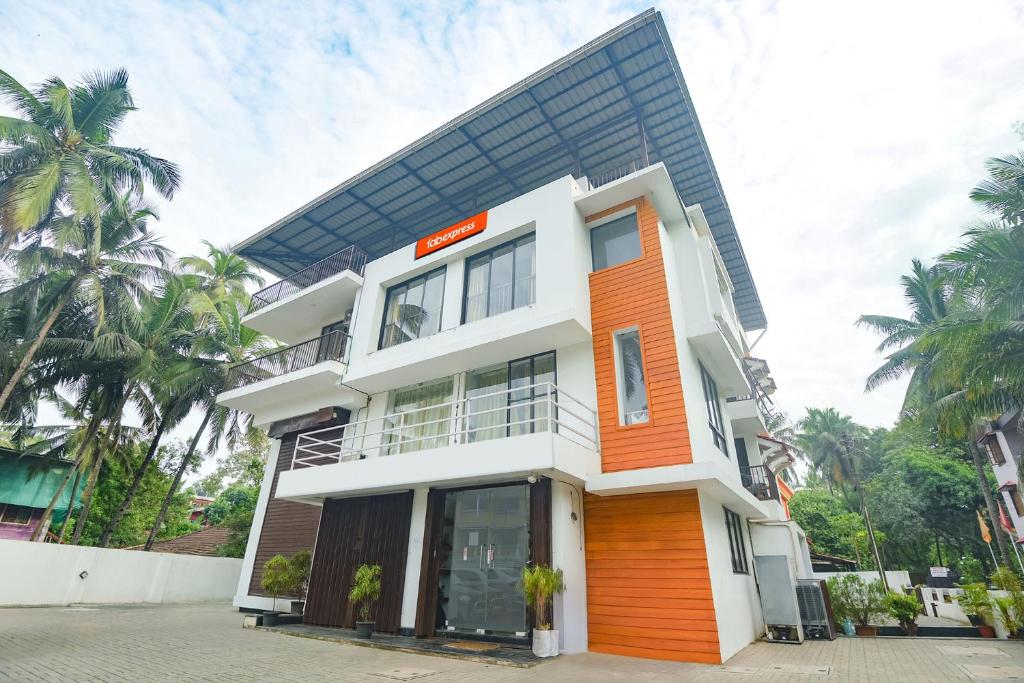 una casa con facciata arancione e bianca di FabExpress Holiday Suites - Nr Benaulim Beach a Benaulim