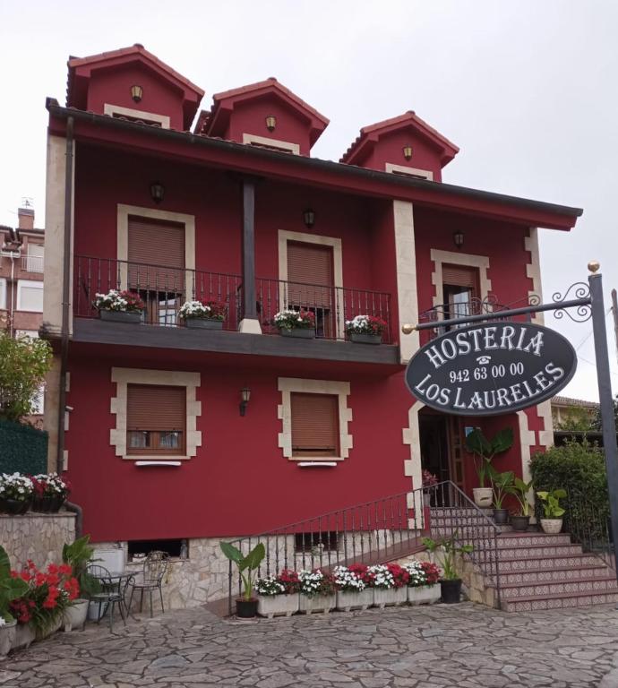 a red building with a sign in front of it at Hosteria Los Laureles in Noja