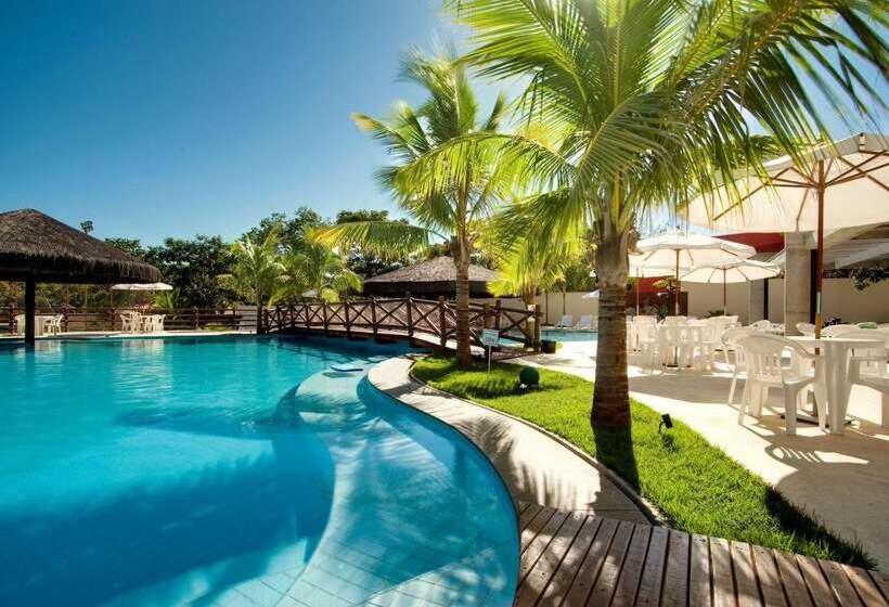 a swimming pool with palm trees and white chairs at Le Jardin Suites Luxo - Central de Reservas in Caldas Novas