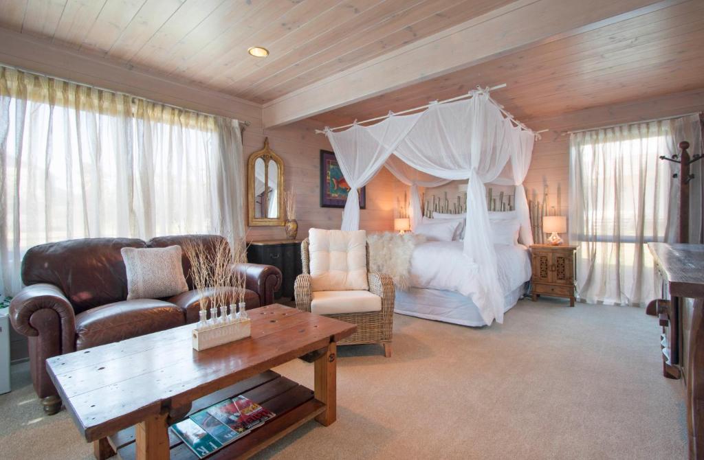 ein Schlafzimmer mit einem Himmelbett in einem Zimmer in der Unterkunft Two Bare Feet in Waihi Beach