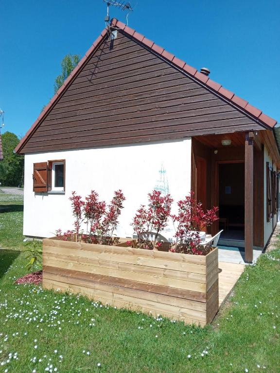 une petite maison avec un planteur en bois dans la cour dans l'établissement Marina près du Lac, à Giffaumont