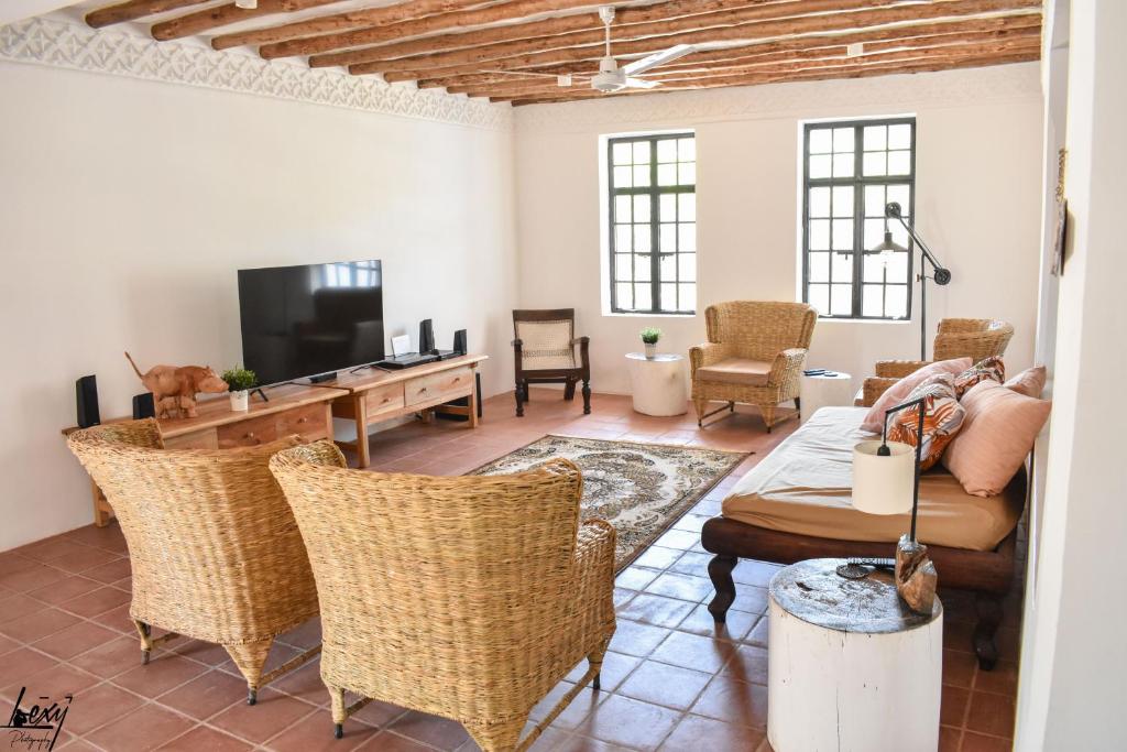 a living room with a couch and chairs and a television at Villa CasaGrande in Ukunda Airport