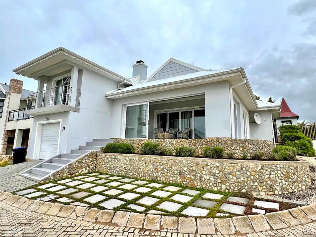 a white house with a stone wall at Waves Edge at 14 Bridge Waters in Jeffreys Bay