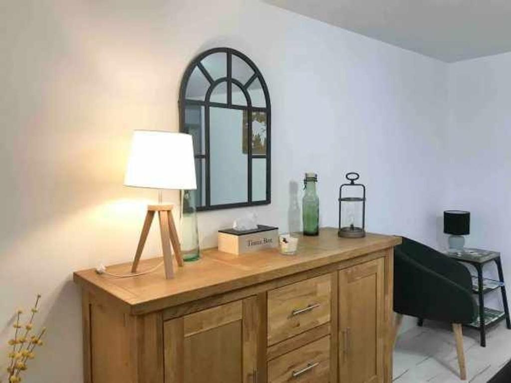a lamp on top of a wooden dresser with a mirror at Charmant Gîte à Neufchâteau Proche Domrémy-la-Pucelle - FR-1-589-797 in Neufchâteau