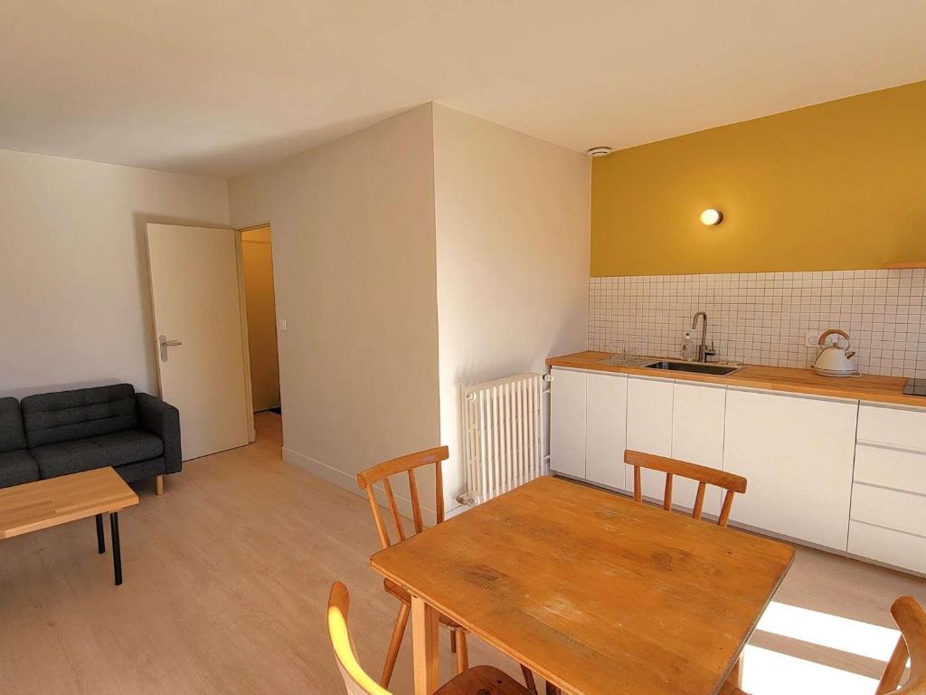 une cuisine et un salon avec une table et un canapé dans l'établissement Appartement T2 rénové - 2 pers - Centre St Bonnet - FR-1-393-180, à Saint-Bonnet-en-Champsaur