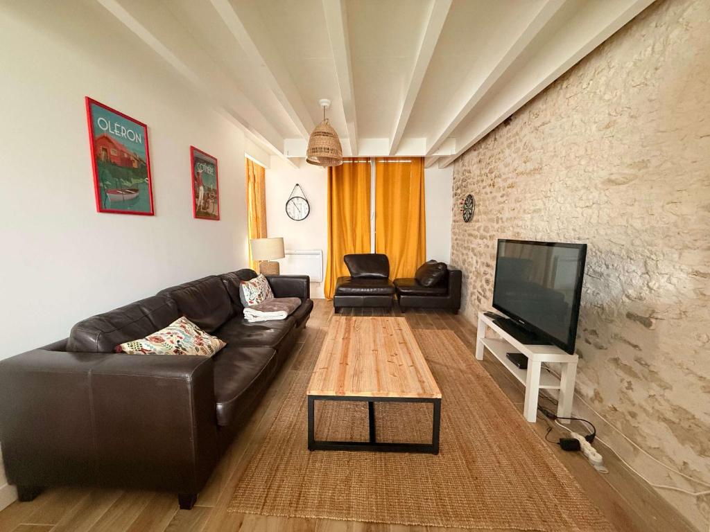 - un salon avec un canapé en cuir et une télévision à écran plat dans l'établissement Ancien chai rénové à Oléron, idéal familles, proche mer - FR-1-778-46, à Saint-Pierre-dʼOléron