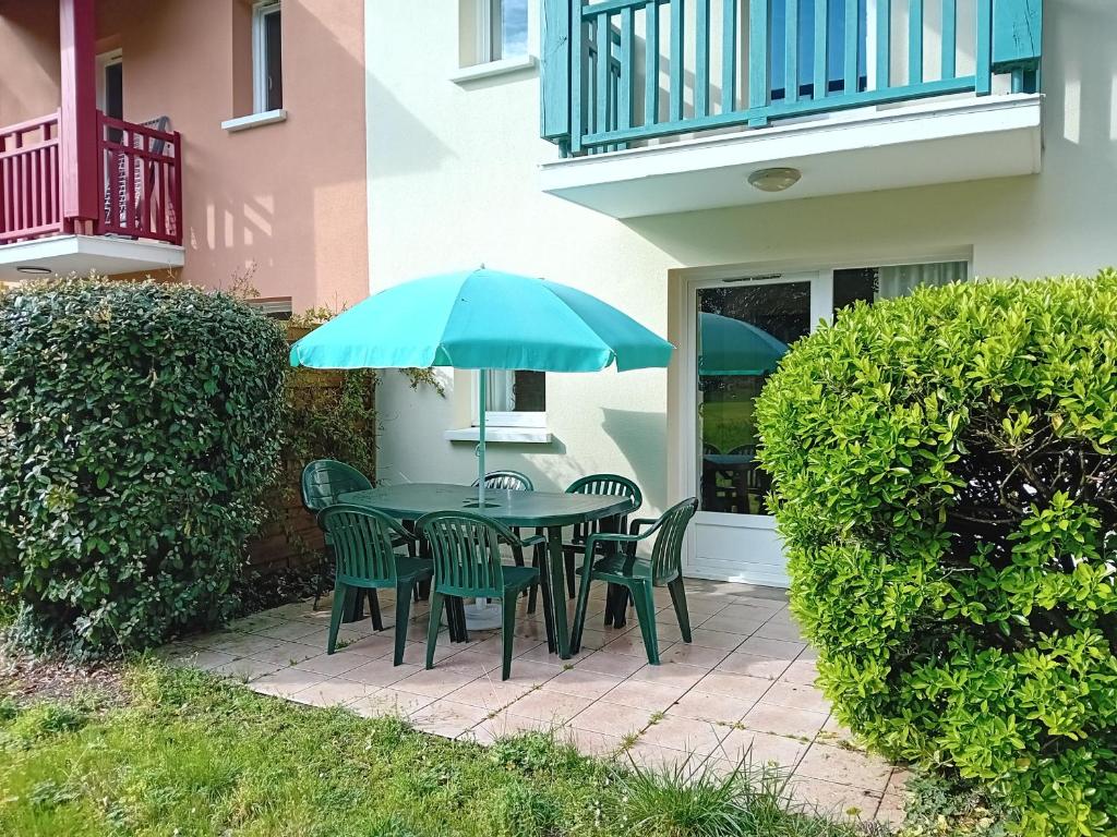 une table et des chaises avec un parasol sur une terrasse dans l'établissement Appartement T3 à Soustons plage - Animaux admis - FR-1-239-1109, à Soustons