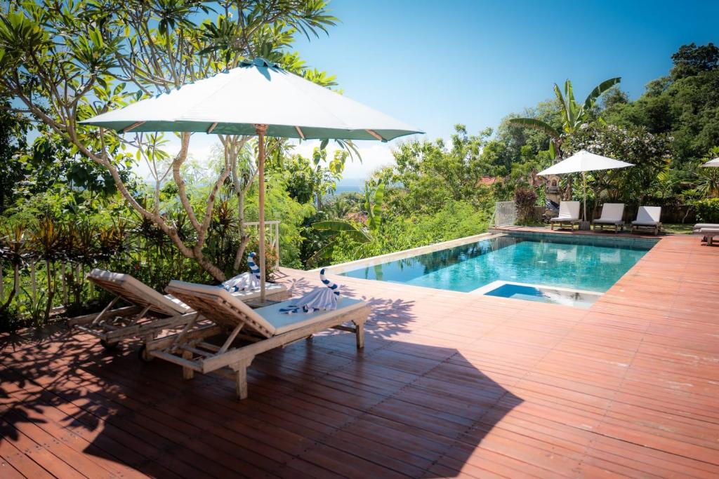a patio with a table and an umbrella next to a pool at La Gautch Bungalow in Nusa Lembongan