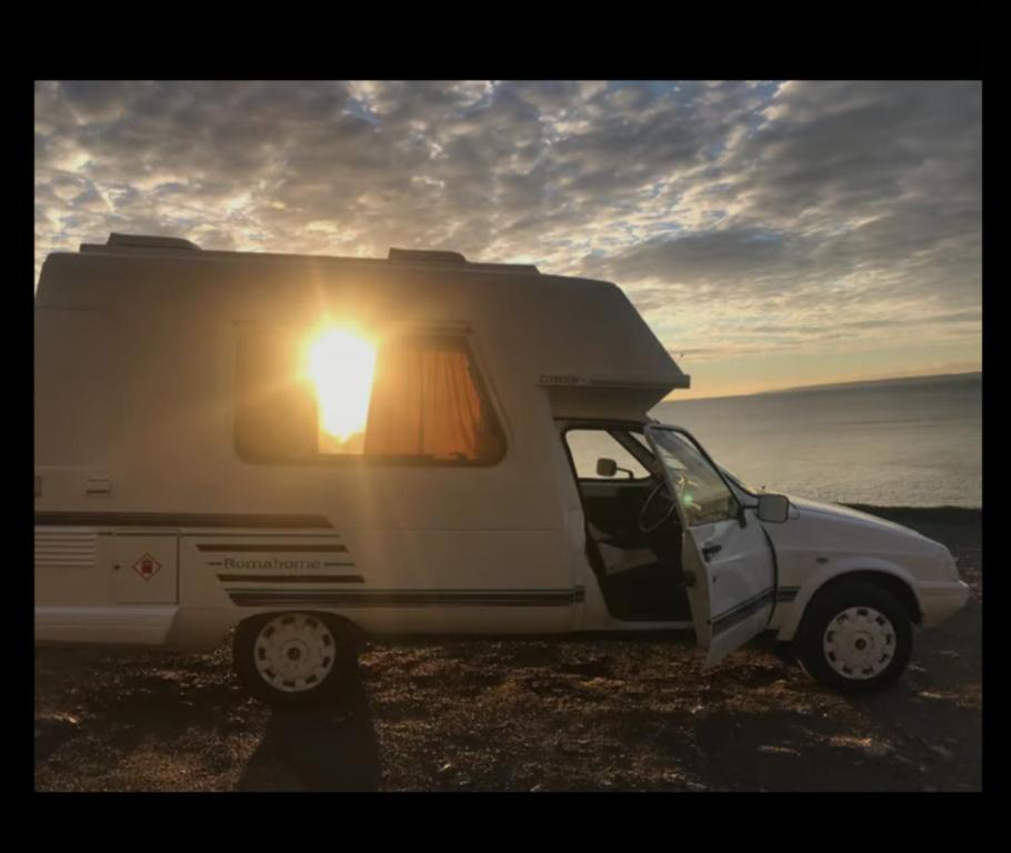 un camper bianco con la porta aperta e il sole splendente di Romahome double camper with Sea View a Porthleven