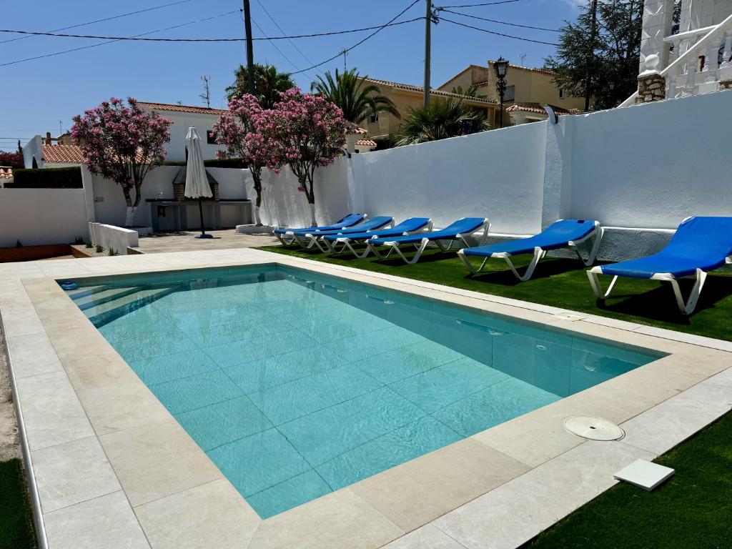 a swimming pool with blue chairs and a fence at Retama Somhome Peñiscola in Peñíscola